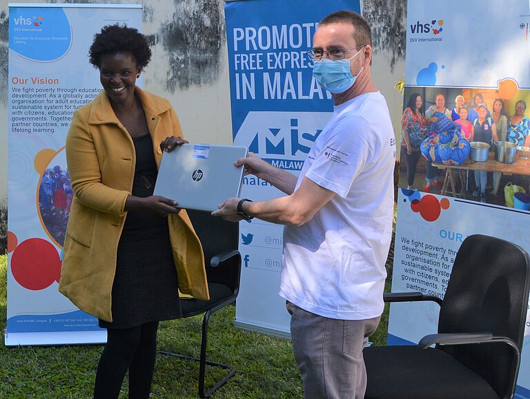 [Translate to English:] Wezzie Gausi erhält den Laptop von David Harrington, Regionalleiter DVV International Südliches Afrika