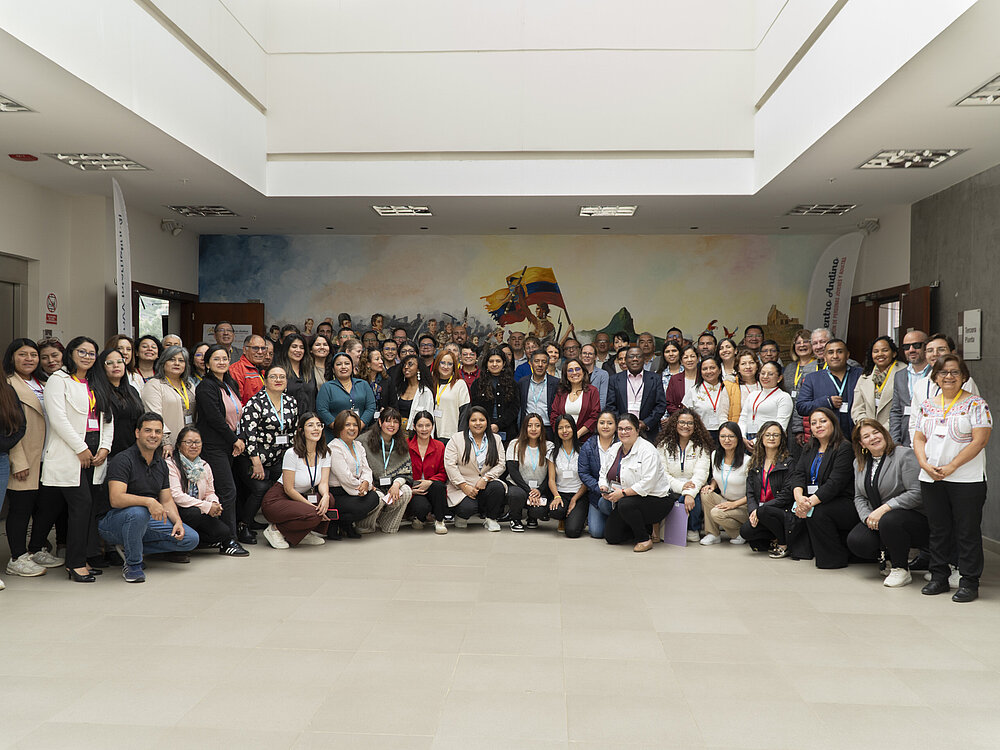 A large group of people stand together for a group photo and look into the camera.