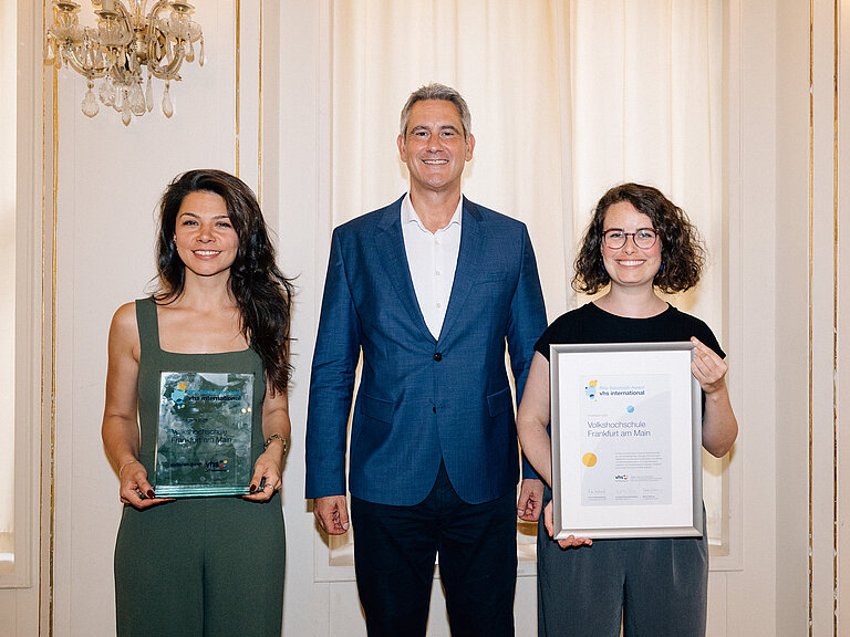 Die PreisträgerInnen der vhs Frankfurt am Main stehen nebeneinander und halten ihre Auszeichnung und Urkunde.