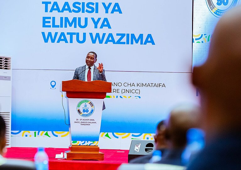 A man stands in front of a speaker's podium.