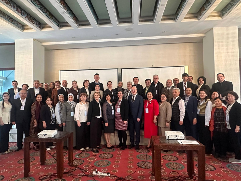 Gruppenfoto von rund 40 Menschen in einem Konferenzsaal. Die Personen tragen überwiegend Business- oder Smart-Casual-Kleidung sowie Namensschilder.