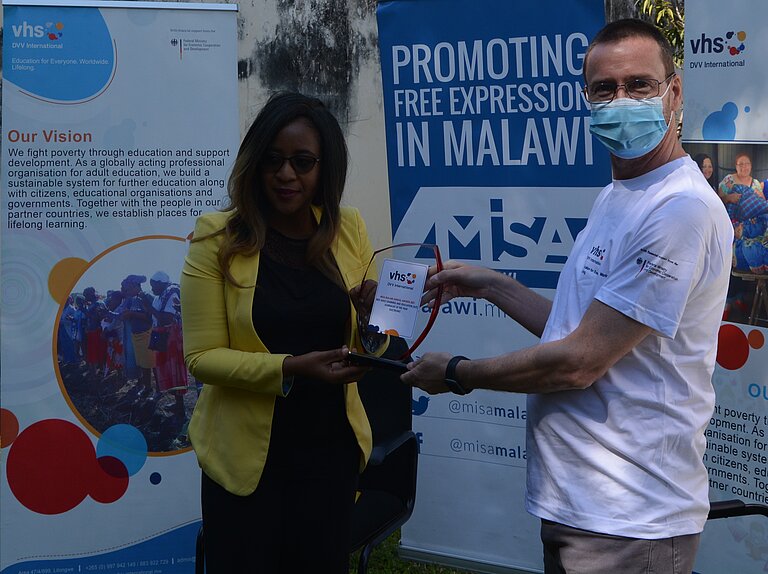 Brenda Kaonga receives the trophy from David Harrington, Regional Director DVV International Southern Africa