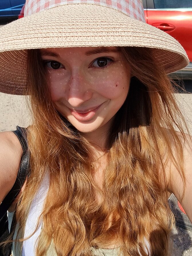 Eine junge Frau blickt lächelnd in die Kamera