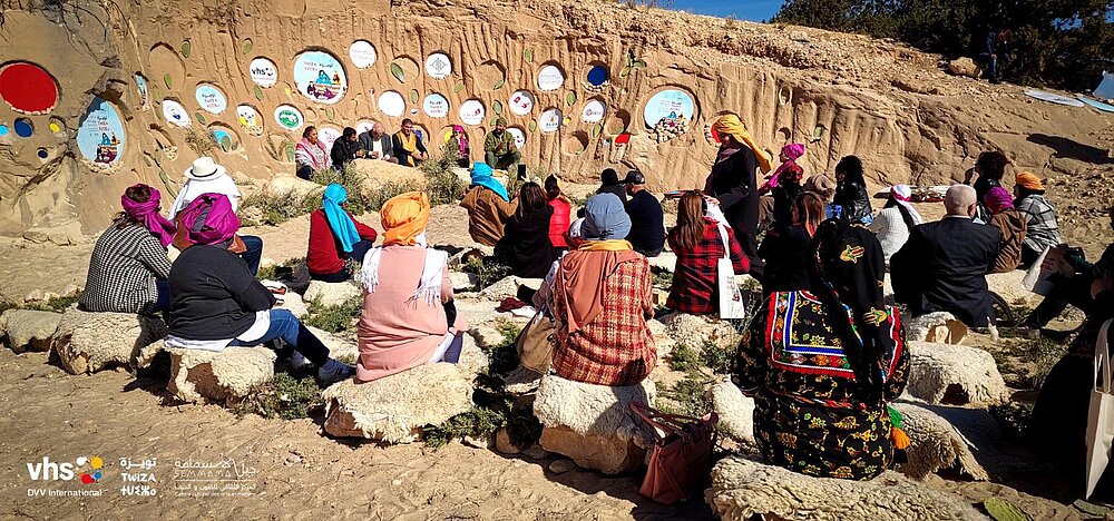 People assembling in a valley, DVV International logo