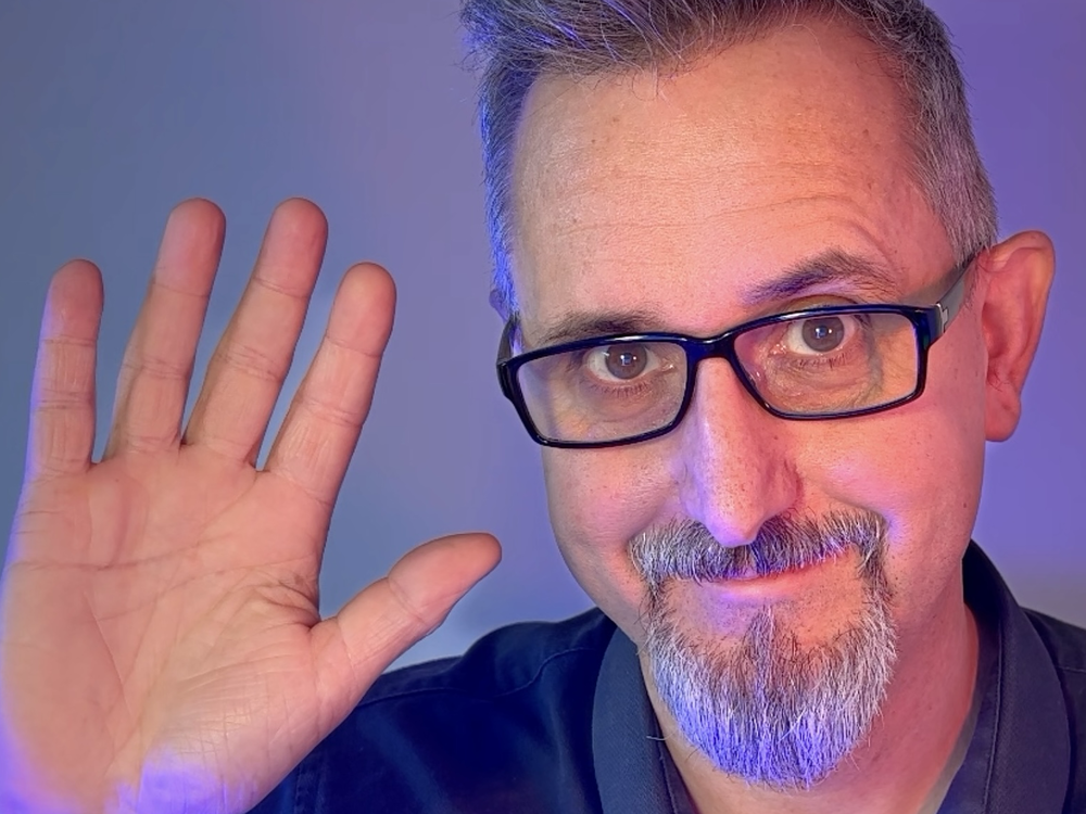 A man waves into the camera.