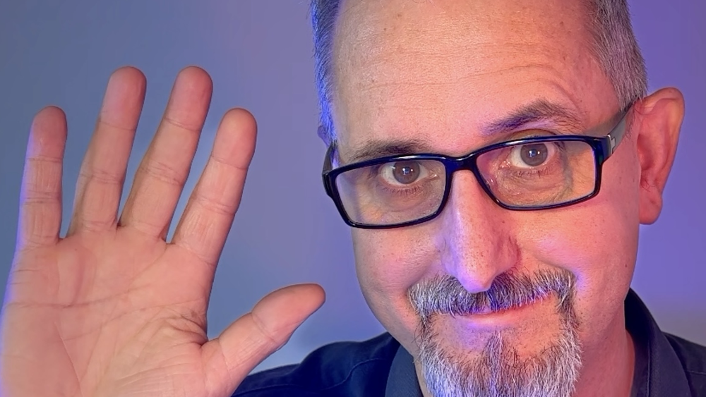 Ein Mann winkt in die Kamera.